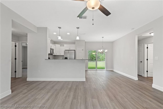 unfurnished living room with ceiling fan with notable chandelier and light wood-type flooring