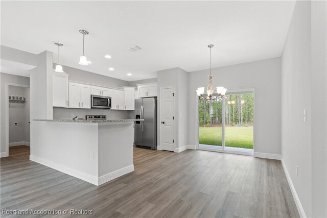 kitchen with kitchen peninsula, appliances with stainless steel finishes, light wood-type flooring, pendant lighting, and white cabinetry