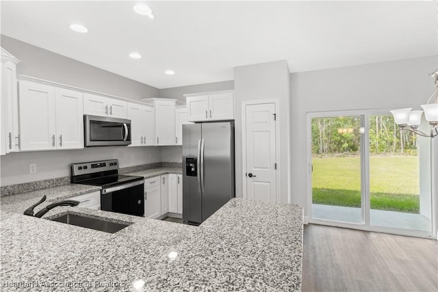 kitchen featuring sink, light stone countertops, light hardwood / wood-style floors, white cabinetry, and stainless steel appliances