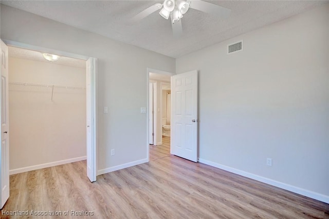 unfurnished bedroom featuring ceiling fan, a closet, light hardwood / wood-style floors, and a textured ceiling