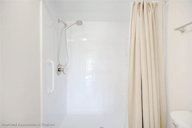 bathroom featuring toilet and curtained shower