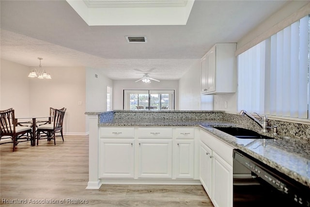 kitchen with dishwasher, ceiling fan with notable chandelier, sink, light stone countertops, and white cabinetry