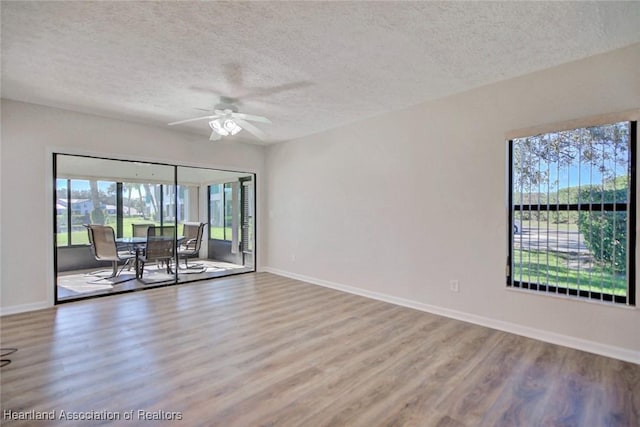 spare room with a wealth of natural light, a textured ceiling, hardwood / wood-style flooring, and ceiling fan