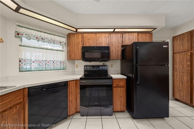 kitchen with light tile patterned floors, black appliances, and a textured ceiling