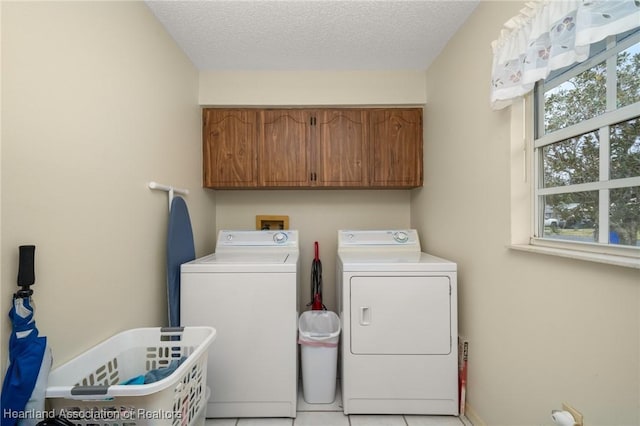 washroom with light tile patterned flooring, cabinets, a textured ceiling, and washing machine and dryer