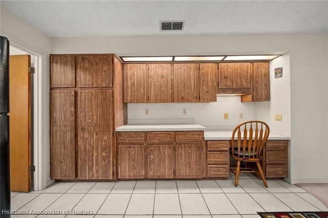 kitchen with tasteful backsplash, light tile patterned floors, and built in desk