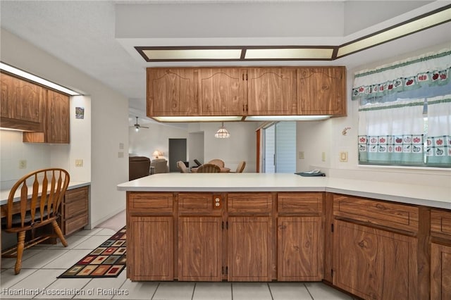 kitchen with ceiling fan, decorative backsplash, kitchen peninsula, and light tile patterned floors