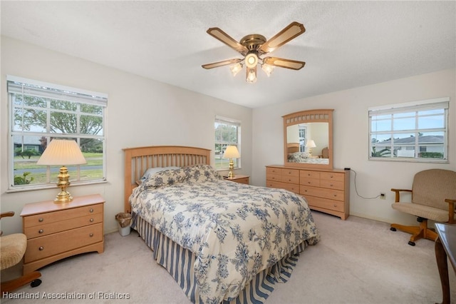 bedroom featuring a textured ceiling, ceiling fan, and light carpet