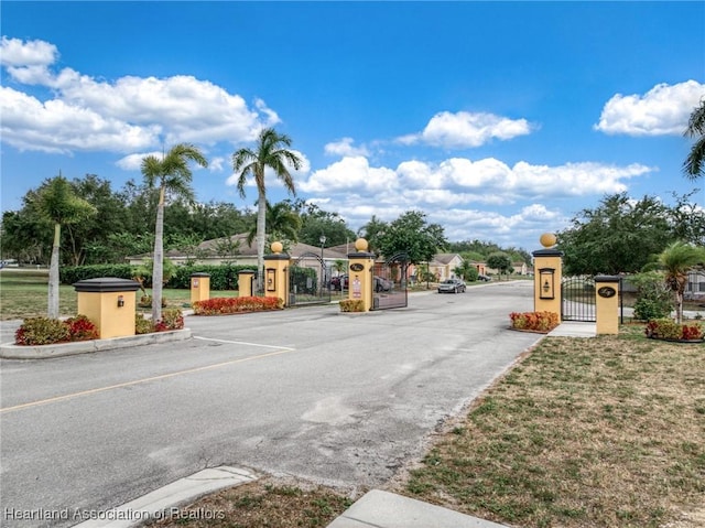 view of street with a gate, curbs, and a gated entry