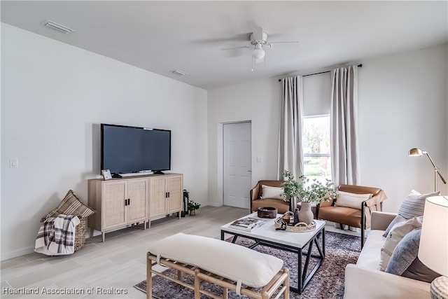 living room with light wood finished floors, baseboards, visible vents, and a ceiling fan