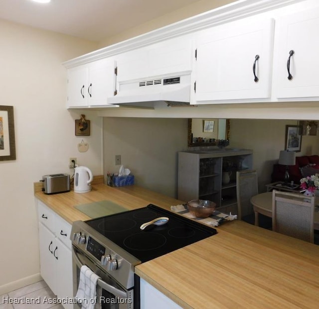 kitchen with under cabinet range hood, light tile patterned floors, white cabinetry, and electric stove