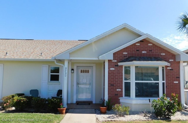 view of front of property featuring a shingled roof and brick siding