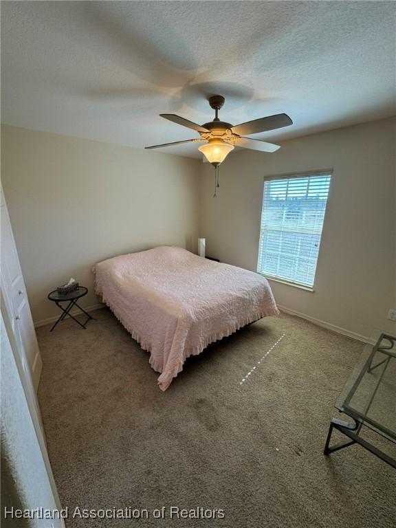 bedroom with ceiling fan, carpet floors, and a textured ceiling