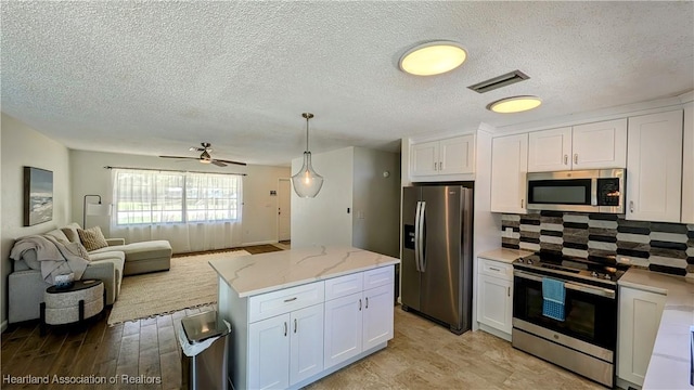 kitchen with white cabinets, stainless steel appliances, and hanging light fixtures