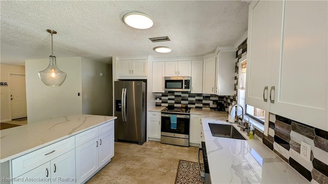 kitchen featuring appliances with stainless steel finishes, decorative light fixtures, white cabinetry, and sink