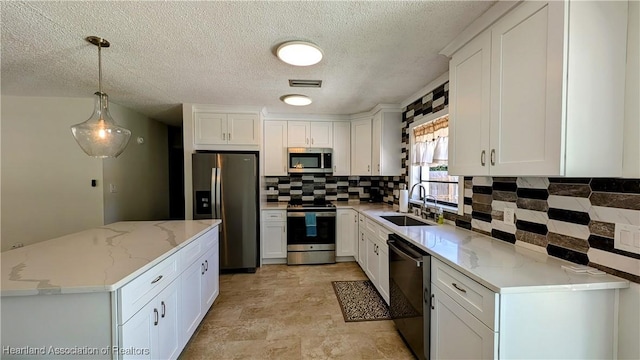 kitchen with light stone countertops, sink, pendant lighting, white cabinets, and appliances with stainless steel finishes