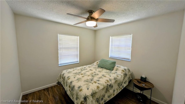 bedroom featuring a textured ceiling, ceiling fan, dark wood-type flooring, and multiple windows