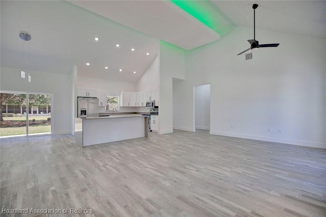 unfurnished living room featuring ceiling fan, light hardwood / wood-style flooring, high vaulted ceiling, and sink