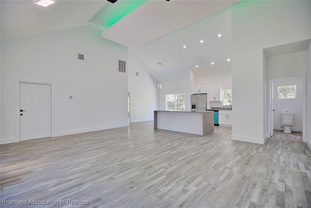 unfurnished living room with high vaulted ceiling and light hardwood / wood-style flooring