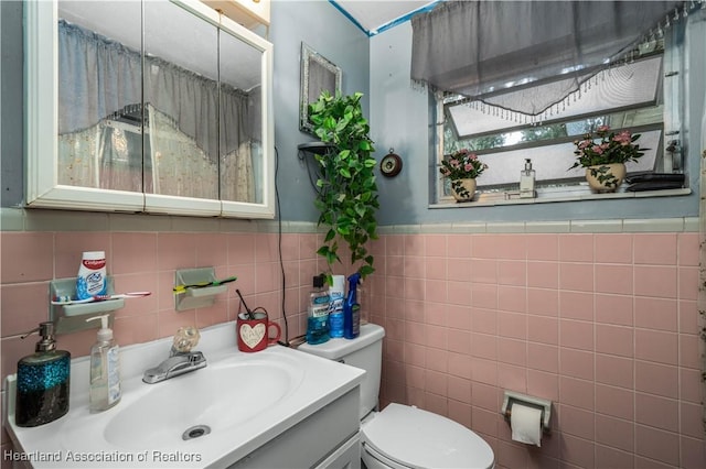 bathroom with vanity, toilet, and tile walls