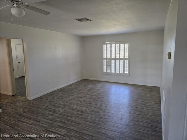 spare room with baseboards, a ceiling fan, dark wood-type flooring, and visible vents
