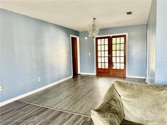 interior space featuring a chandelier, french doors, a textured ceiling, and wood-type flooring