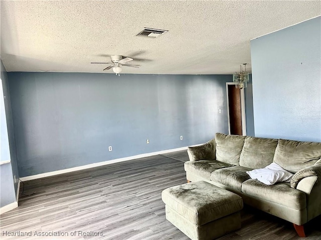 living room featuring ceiling fan, wood-type flooring, and a textured ceiling