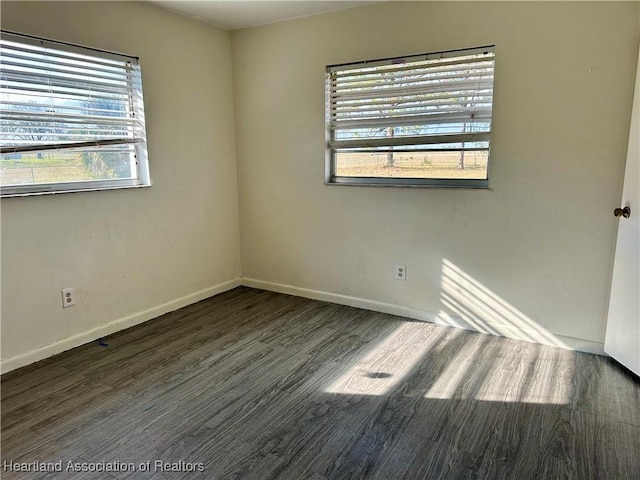 empty room featuring plenty of natural light and dark wood-type flooring