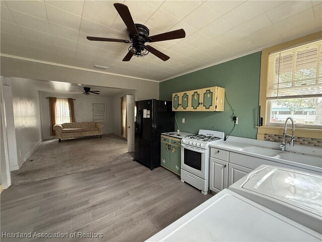 351 N Commerce Ave, Sebring, FL 33870 - kitchen featuring white gas range oven, black refrigerator with ice dispenser, ceiling fan, light wood-type flooring, and a sink