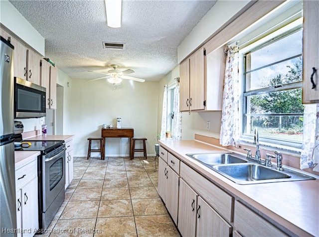 kitchen featuring stainless steel appliances, ceiling fan, sink, and light brown cabinetry