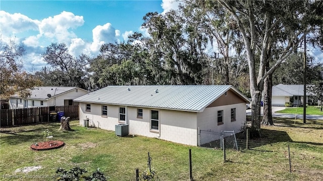 rear view of property featuring central AC unit and a yard