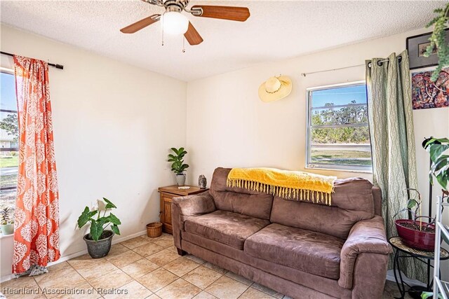 living room featuring ceiling fan, light tile patterned floors, and a textured ceiling