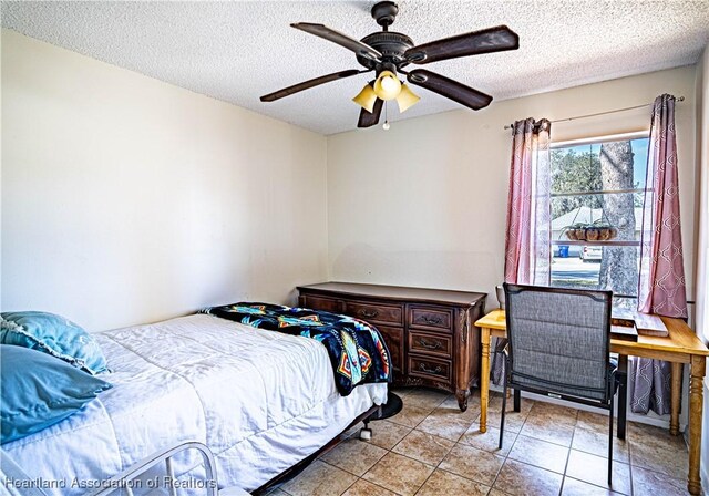 bedroom featuring ceiling fan, a textured ceiling, and light tile patterned floors