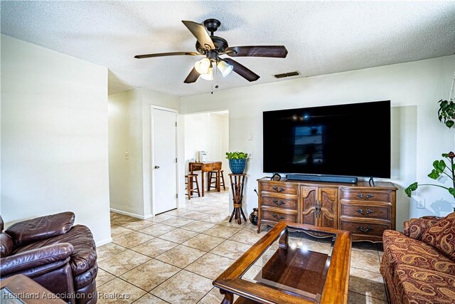 tiled living room with ceiling fan and a textured ceiling