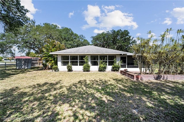 back of house featuring a lawn, fence, an outdoor structure, and a sunroom