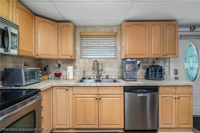 kitchen featuring appliances with stainless steel finishes, a paneled ceiling, tasteful backsplash, and sink