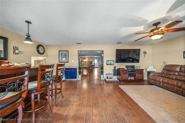 living room featuring a textured ceiling, ceiling fan, and dark wood-type flooring