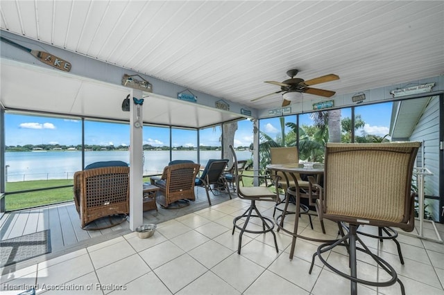 sunroom featuring ceiling fan and a water view