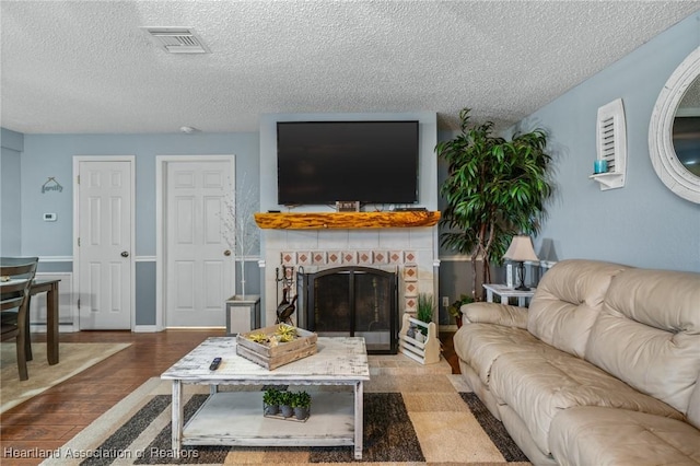 living room featuring a fireplace, hardwood / wood-style floors, and a textured ceiling