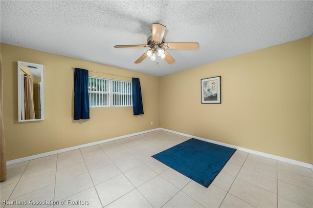 unfurnished room featuring ceiling fan, light tile patterned floors, and a textured ceiling