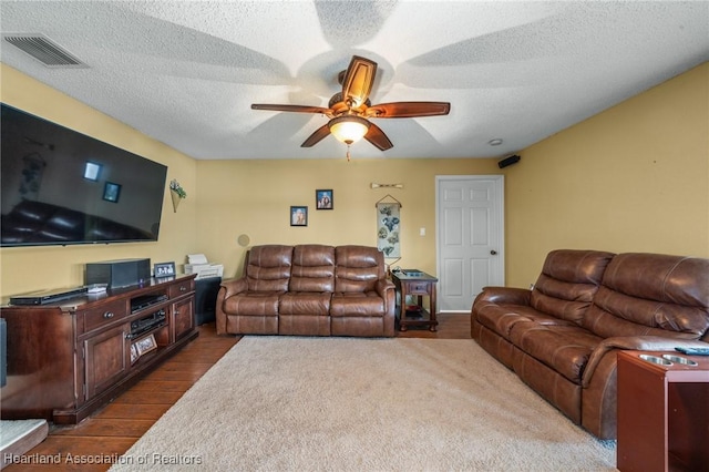 living room with ceiling fan, dark hardwood / wood-style floors, and a textured ceiling