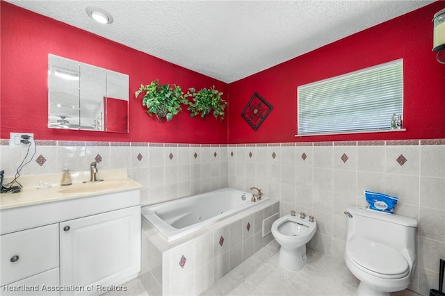 bathroom with a relaxing tiled tub, a bidet, a textured ceiling, toilet, and vanity