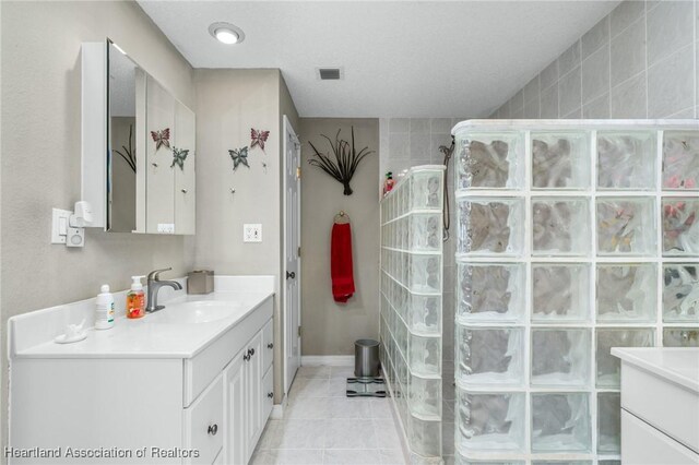 bathroom featuring tile patterned flooring, vanity, and a shower