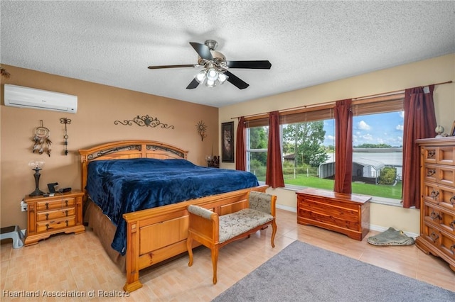 bedroom with ceiling fan, an AC wall unit, and a textured ceiling