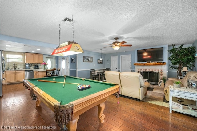 game room with a brick fireplace, ceiling fan, dark hardwood / wood-style floors, and pool table