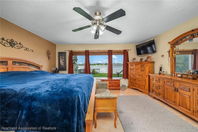 bedroom with light wood-type flooring, a textured ceiling, and ceiling fan