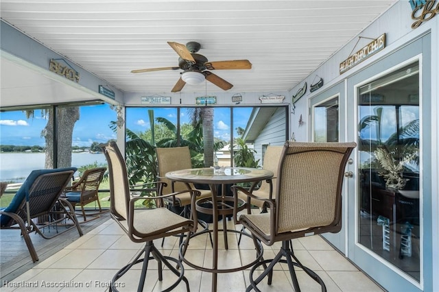 sunroom / solarium with ceiling fan and a water view