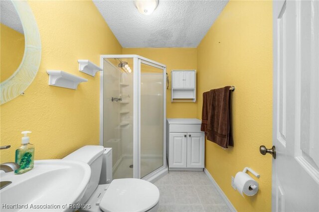 bathroom with sink, an enclosed shower, a textured ceiling, and toilet