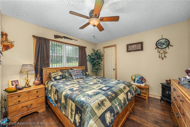 bedroom with a textured ceiling, ceiling fan, and dark wood-type flooring