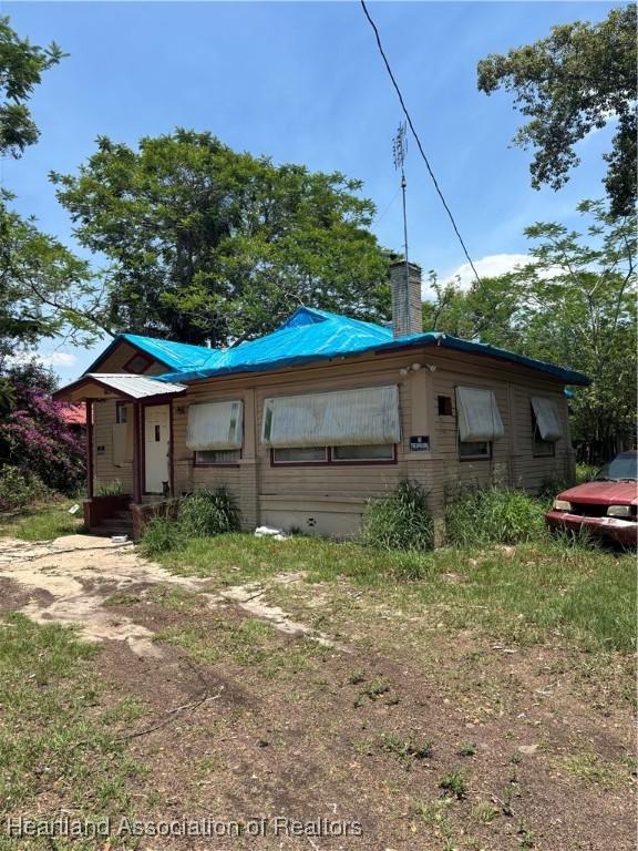 607 S Willow Ave, Avon Park, FL 33825 - rear view of house with a chimney, metal roof, and crawl space